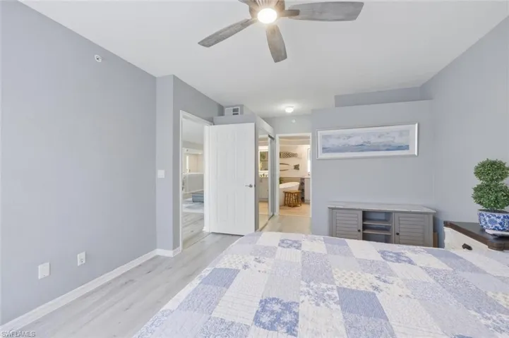Bedroom with light wood-type flooring, ensuite bath, and ceiling fan