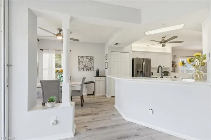 Kitchen featuring a ceiling fan, white cabinetry, stainless steel fridge, and light wood-style floors