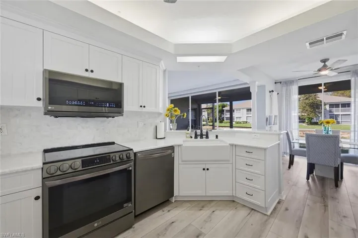 Kitchen featuring a peninsula, stainless steel appliances, ceiling fan, white cabinets, and light wood-type flooring
