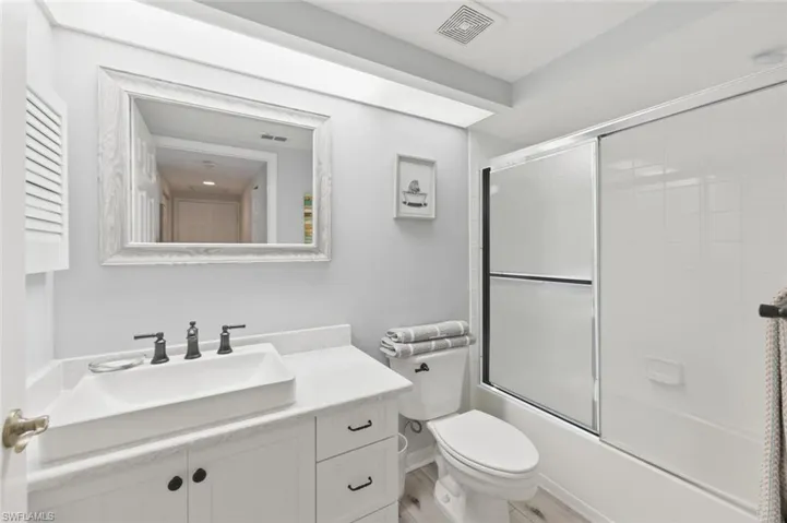 Full bathroom featuring vanity and bath / shower combo with glass door