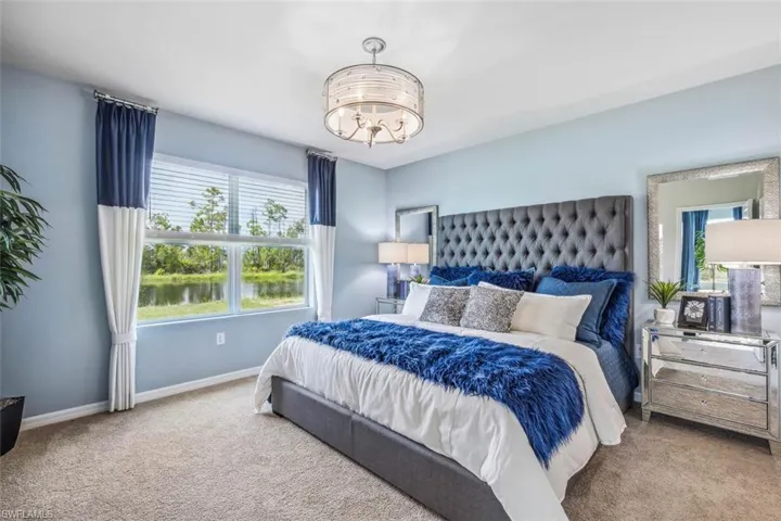 Carpeted bedroom with a chandelier and baseboards
