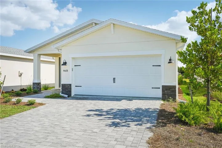 View of front facade with stone siding, decorative driveway, and a garage