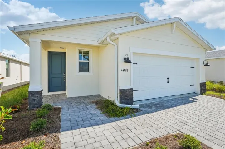 View of front facade featuring stone siding, stucco siding, an attached garage, and decorative driveway