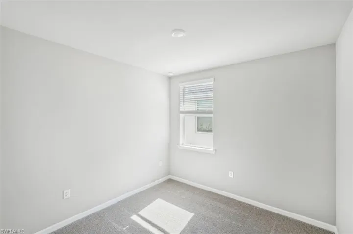 Empty room with light colored carpet and baseboards