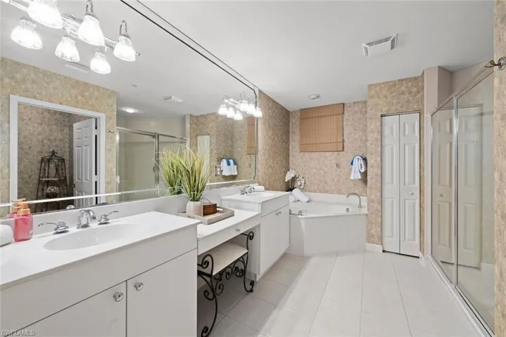 Bathroom with a stall shower, tile patterned floors, a sink, visible vents, and wallpapered walls