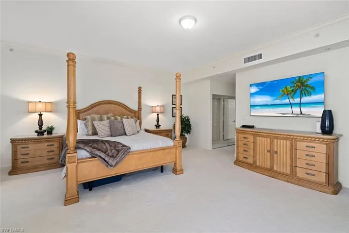 Bedroom with ornamental molding, light colored carpet, and visible vents