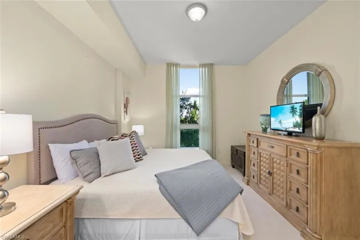 Bedroom featuring light carpet and multiple windows