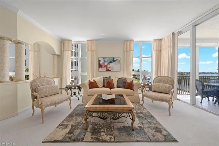Carpeted living area with plenty of natural light, a wall of windows, crown molding, and baseboards