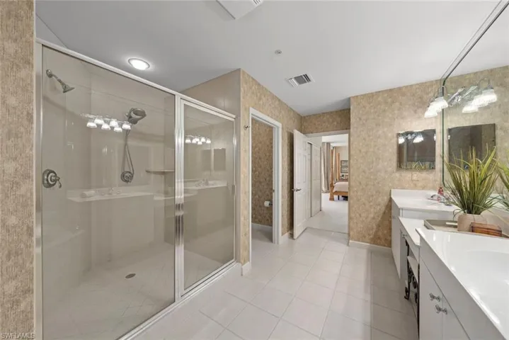Ensuite bathroom featuring visible vents, double vanity, a stall shower, ensuite bath, and tile patterned flooring