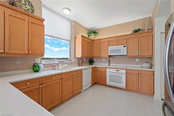 Kitchen featuring white appliances, light countertops, decorative backsplash, and a sink