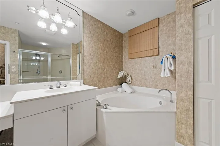 Bathroom with a stall shower, wallpapered walls, vanity, and a garden tub