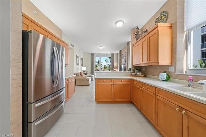 Kitchen featuring freestanding refrigerator, open floor plan, light countertops, and light tile patterned flooring