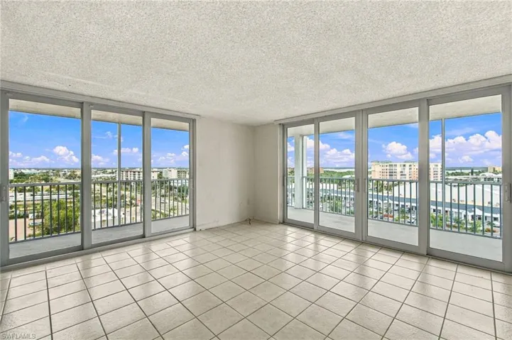 Expansive corner balcony with floor-to-ceiling glass doors and windows framing panoramic cityscape vistas