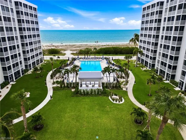 Expansive outdoor area featuring a swimming pool, covered cabana, and direct access to a sandy beach