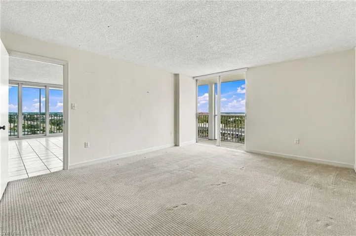 Wall-to-wall carpeting, white painted walls, and sliding glass doors opening to a balcony