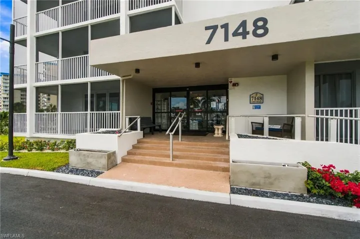 Building entrance with a concrete staircase, handrails, and a ramp