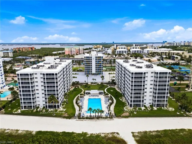 Beachfront high-rise community featuring multiple residential towers, a large swimming pool, and manicured grounds