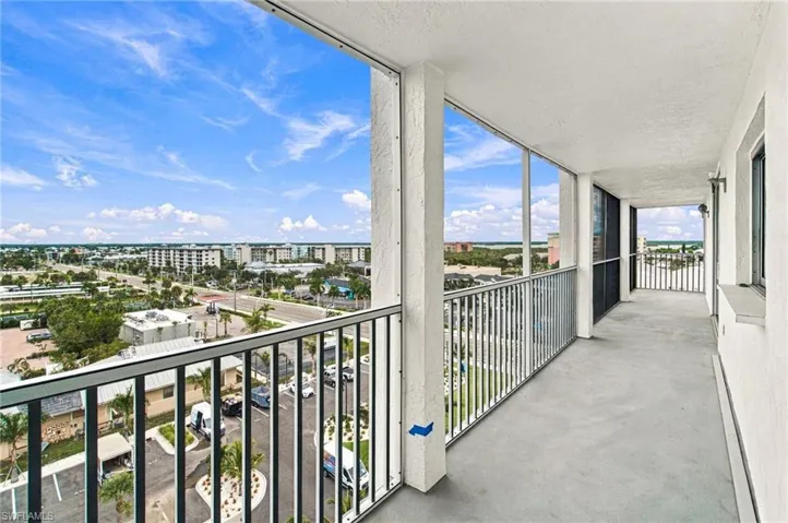 Expansive balcony with concrete flooring, white painted walls, and metal railings