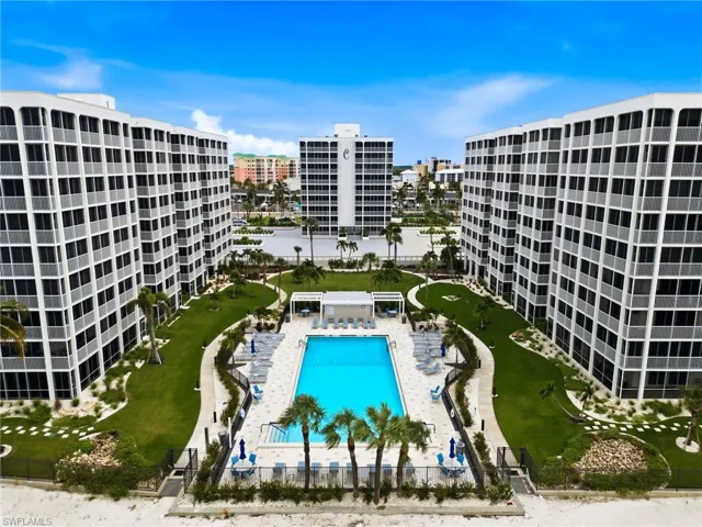 Resort-style pool with surrounding lounge seating, manicured lawn, and paved pathways