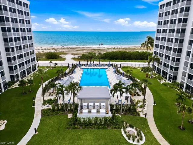 Expansive outdoor area featuring a swimming pool, surrounding lounge seating, and an adjacent building with a covered patio