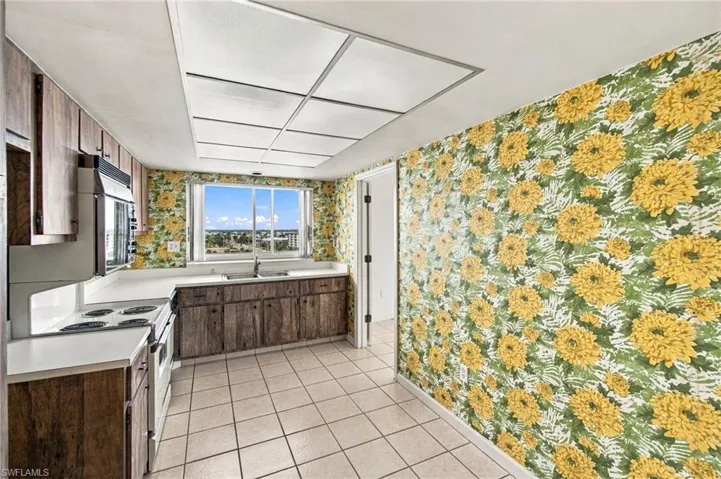 Bright galley kitchen showcasing wood-finish cabinetry, tile flooring, and recessed ceiling lighting
