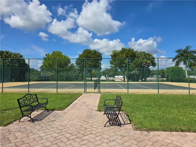 View of community tennis court and a gate