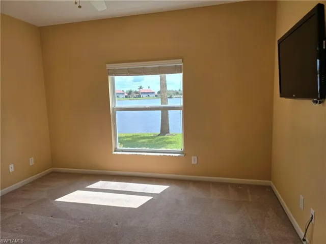 Carpeted 2nd bedroom room with baseboards and ceiling fan and view of lake