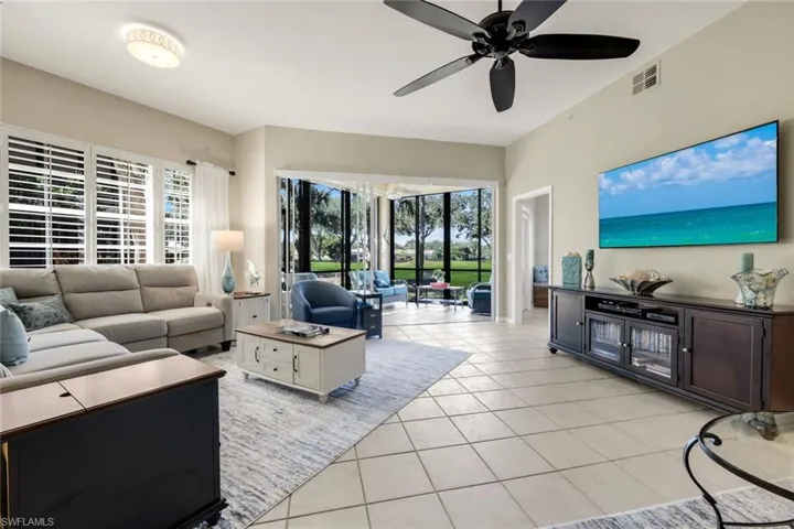 Living area with light tile flooring, a ceiling fan, and lots of ligt.