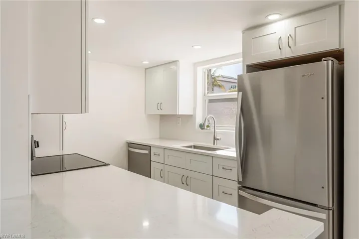 Kitchen with stainless steel appliances, light stone countertops, white cabinetry, recessed lighting, and backsplash