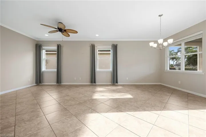 Spare room with crown molding, light tile patterned flooring, a chandelier, recessed lighting, and a ceiling fan
