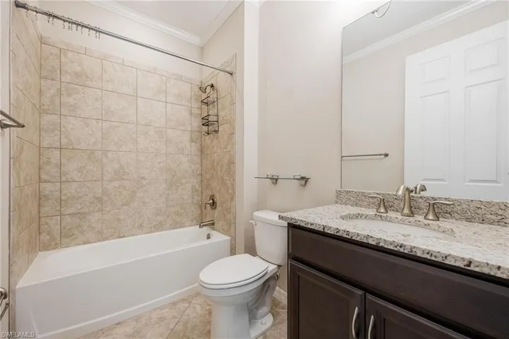 Bathroom featuring shower / tub combination, vanity, light tile patterned floors, and crown molding