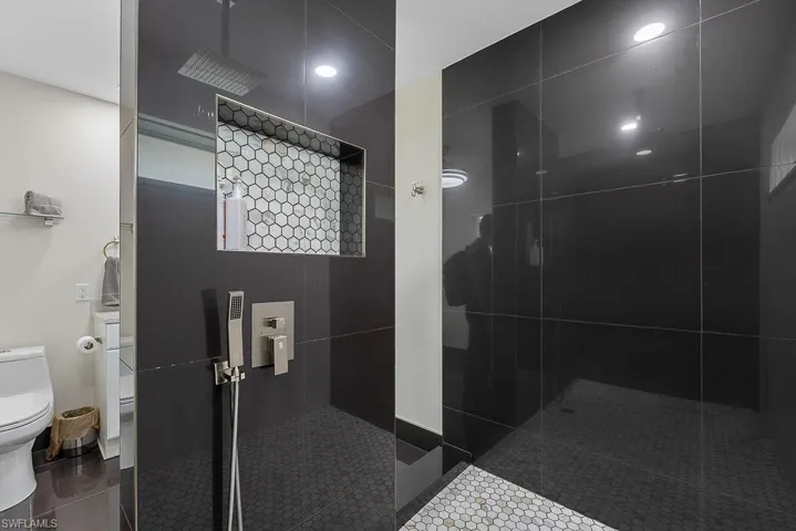 Bathroom featuring walk in shower and dark tile patterned floors