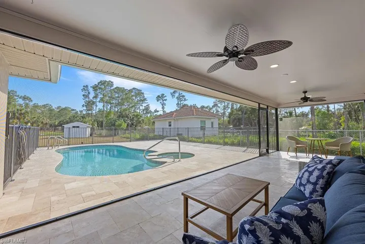 View of pool with an in-ground hot tub, a fenced backyard, a sunroom, and a shed
