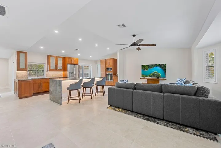 Living room featuring lofted ceiling, recessed lighting, light tile patterned floors, and ceiling fan