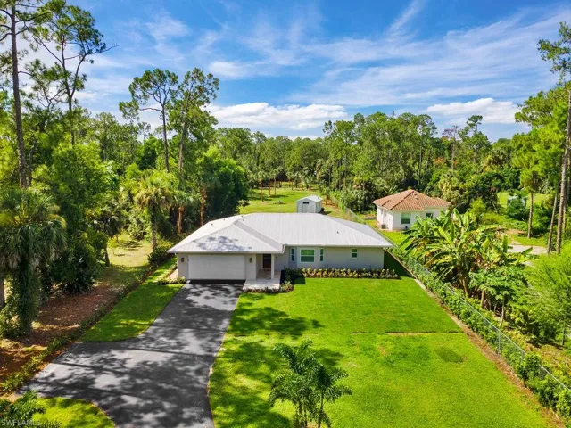 View of subject property featuring a tree filled landscape