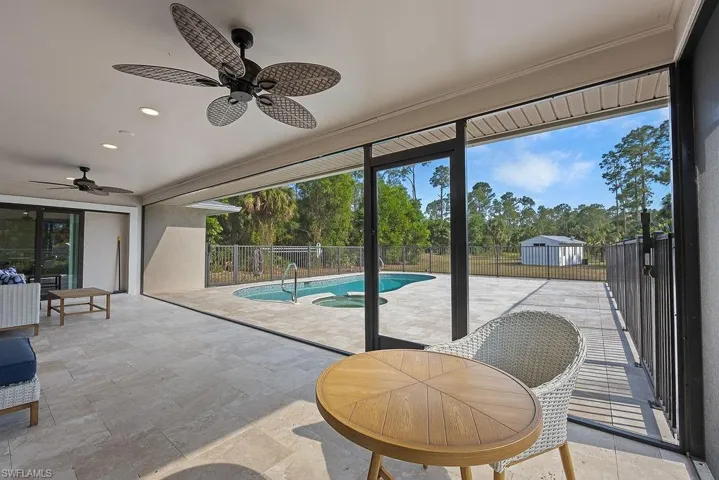 Doorway to outside with plenty of natural light, ceiling fan, a sunroom, recessed lighting, and stone tile floors