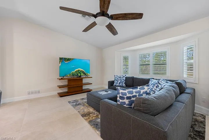 Living room featuring lofted ceiling, a ceiling fan, and light tile patterned flooring