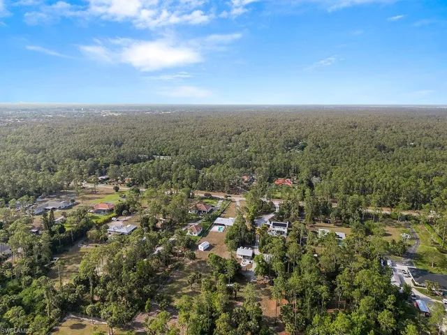 Aerial view of property and surrounding area with a heavily wooded area