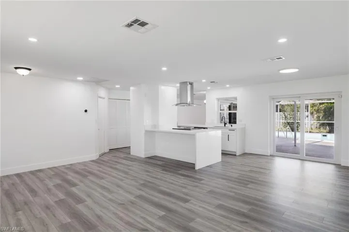 View of Kitchen featuring island range hood, sink, light hardwood / wood-style vinyl flooring, and white cabinetry from Living room