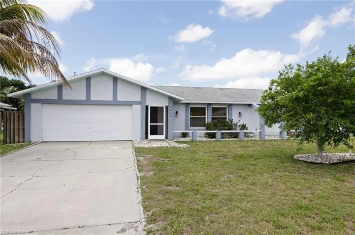 Ranch-style home featuring a garage and a front lawn