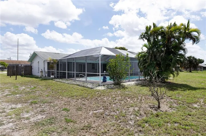 Rear view of house featuring backyard, pool, and a lanai