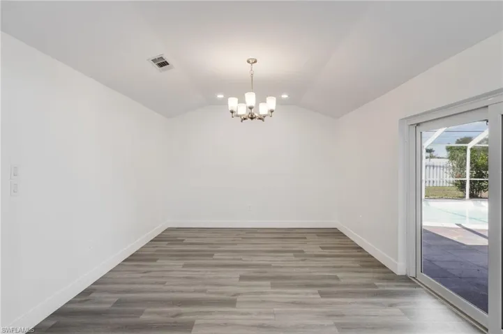 Family room with vaulted ceiling, a chandelier, and sliding door to lanai