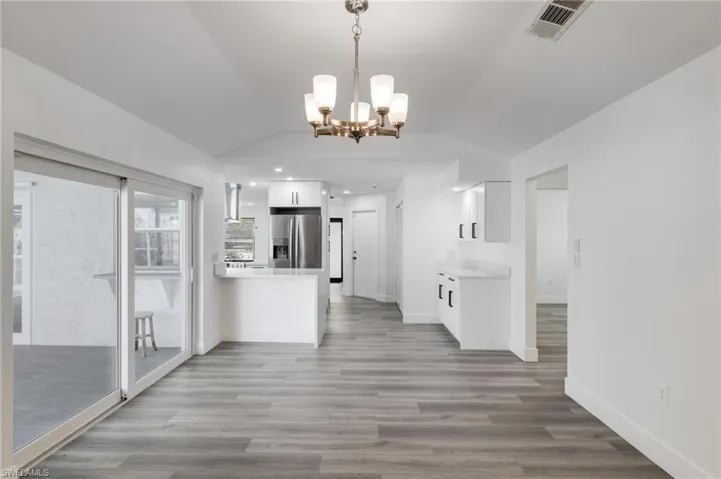 Family room with light wood-type vinyl flooring, vaulted ceiling, and a chandelier