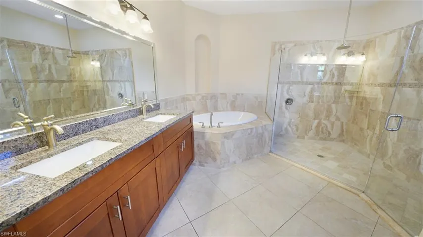 Primary ensuite bath with dual sink granite vanity, luxurious soaking tub, and massing walk-in shower with rain showerhead.