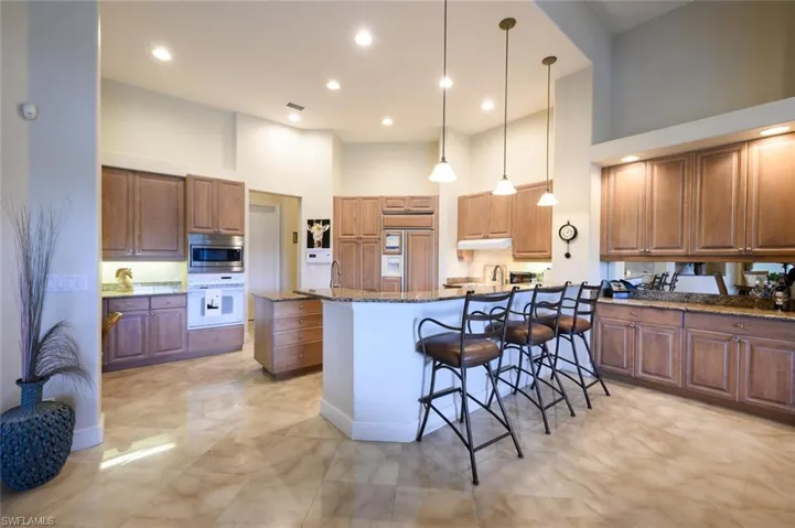 Kitchen featuring a breakfast bar, built in appliances, a high ceiling, and decorative light fixtures