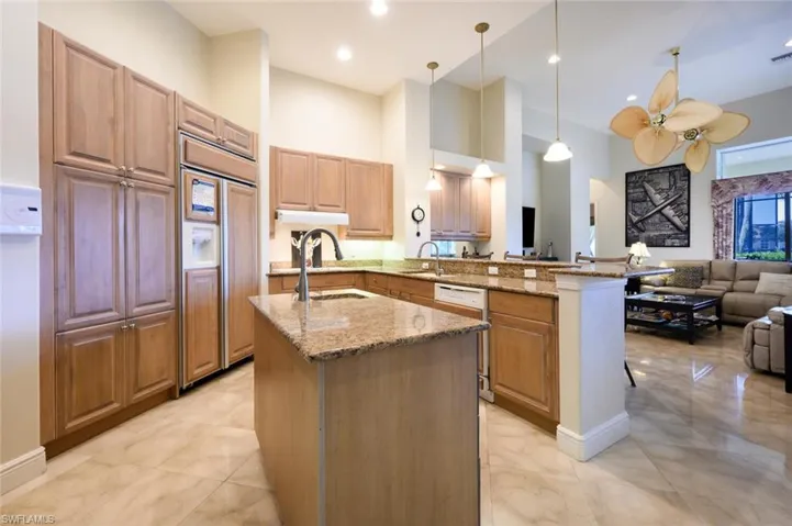 Kitchen featuring ceiling fan, paneled built in refrigerator, light stone countertops, kitchen peninsula, and light tile patterned flooring