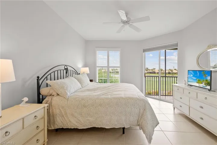 Tiled bedroom with ceiling fan, multiple windows, and access to exterior