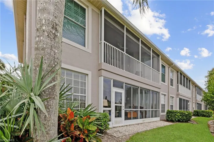 Rear view of property with a lawn and a sunroom