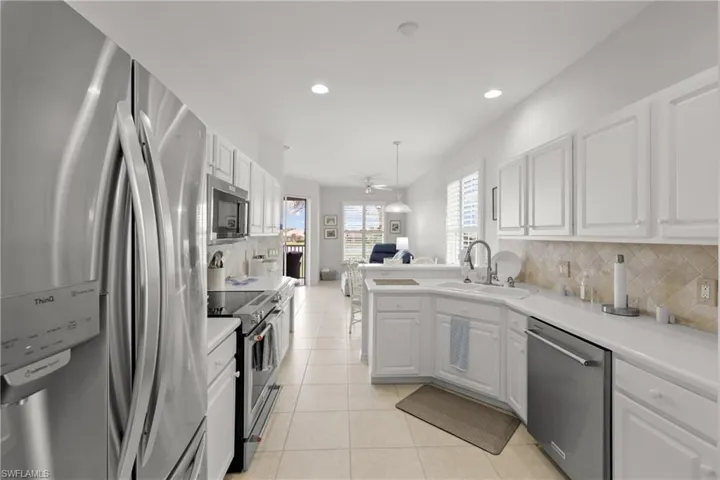 Kitchen with tasteful backsplash, appliances with stainless steel finishes, sink, white cabinetry, and light tile patterned floors