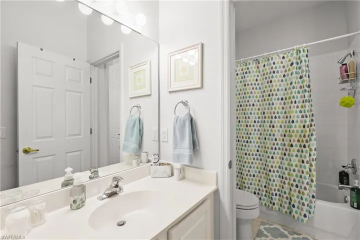 Full bathroom featuring vanity, shower / bath combination with curtain, toilet, and tile patterned floors
